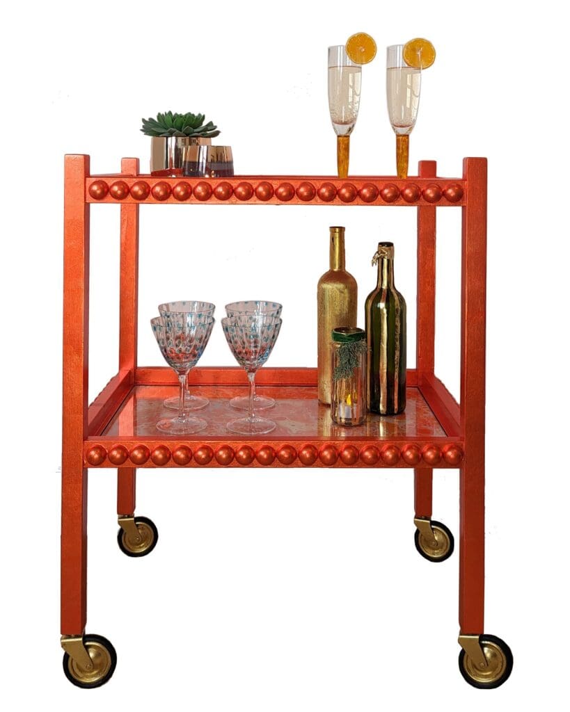 Vintage drinks trolley named Clementine, finished in orange silver leaf with a mid-century modern design, styled with bottles and glasses