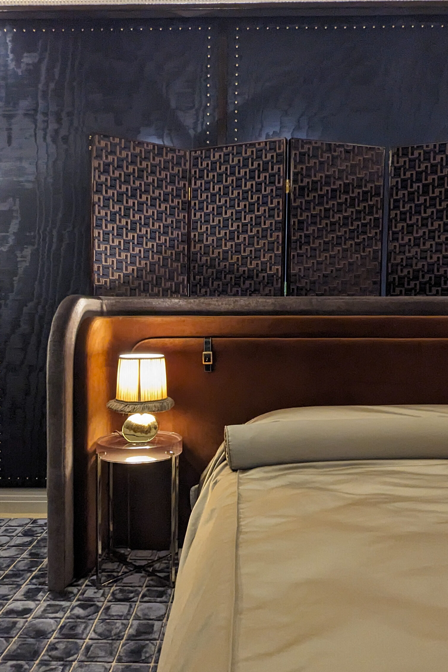 Navy silk walls with a bed in front of a brown curved headboard