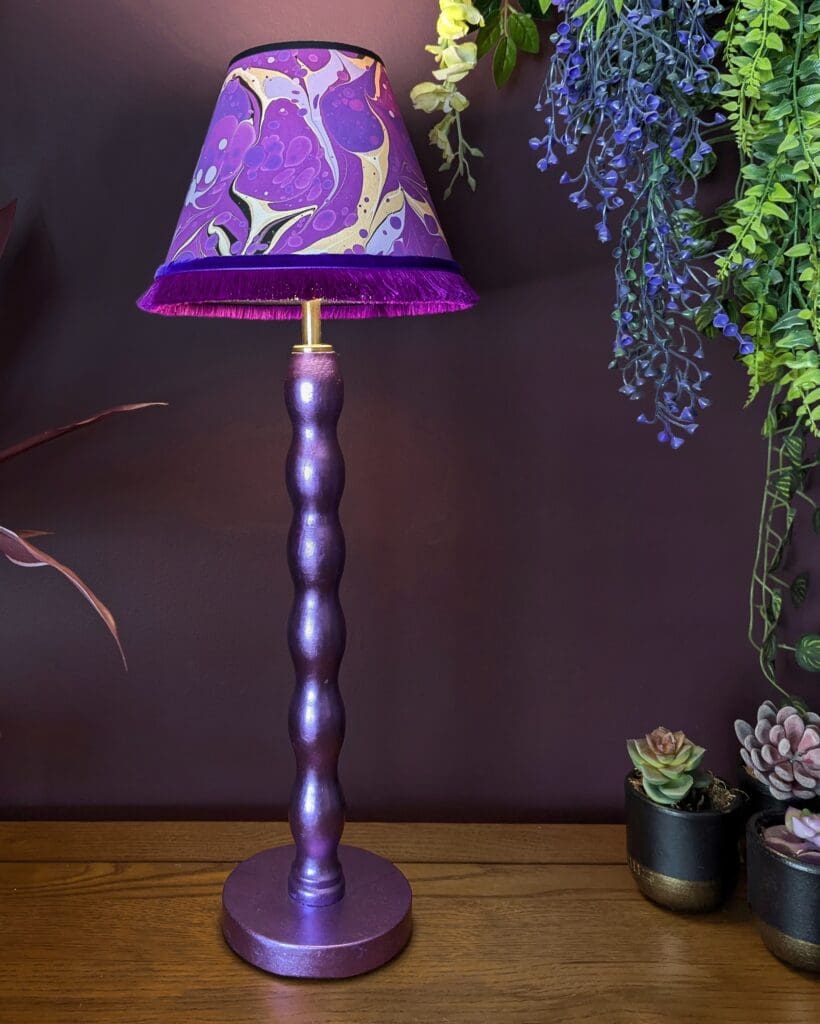 Purple gilded cordless lamp with fringed purple marbled lampshade