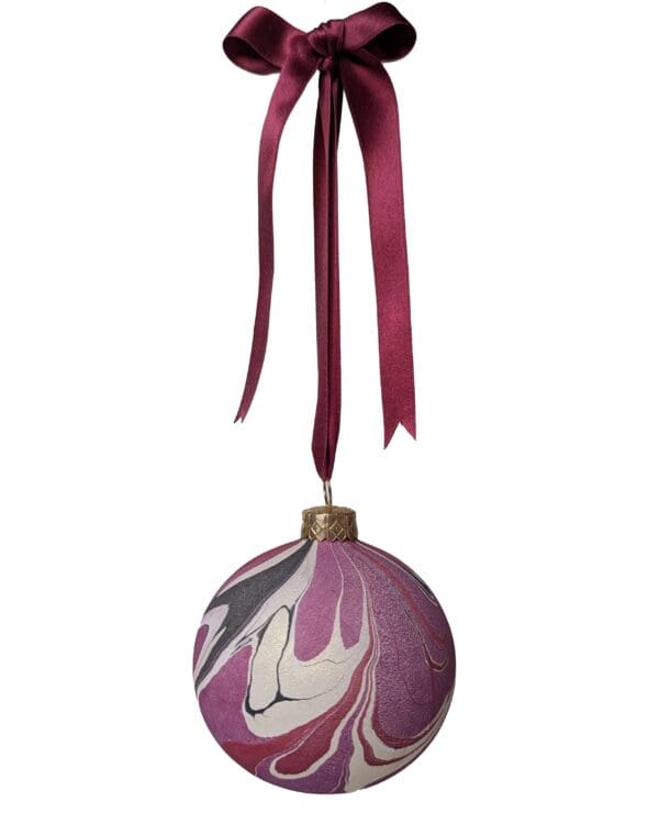 marbled christmas bauble in cherry red, plum, black and gold hanging on dark red satin ribbin with bow